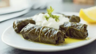 Фото рецепта Греческие долмадес с лимонным соусом: нежные рулетики в виноградных листьях