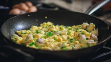 Фото блюда: Рапаны с яйцом и зеленым луком на сковороде для сытного завтрака