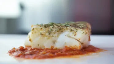 Фото рецепта Запеченная треска в пассерованных томатах: нежное филе под ароматным соусом